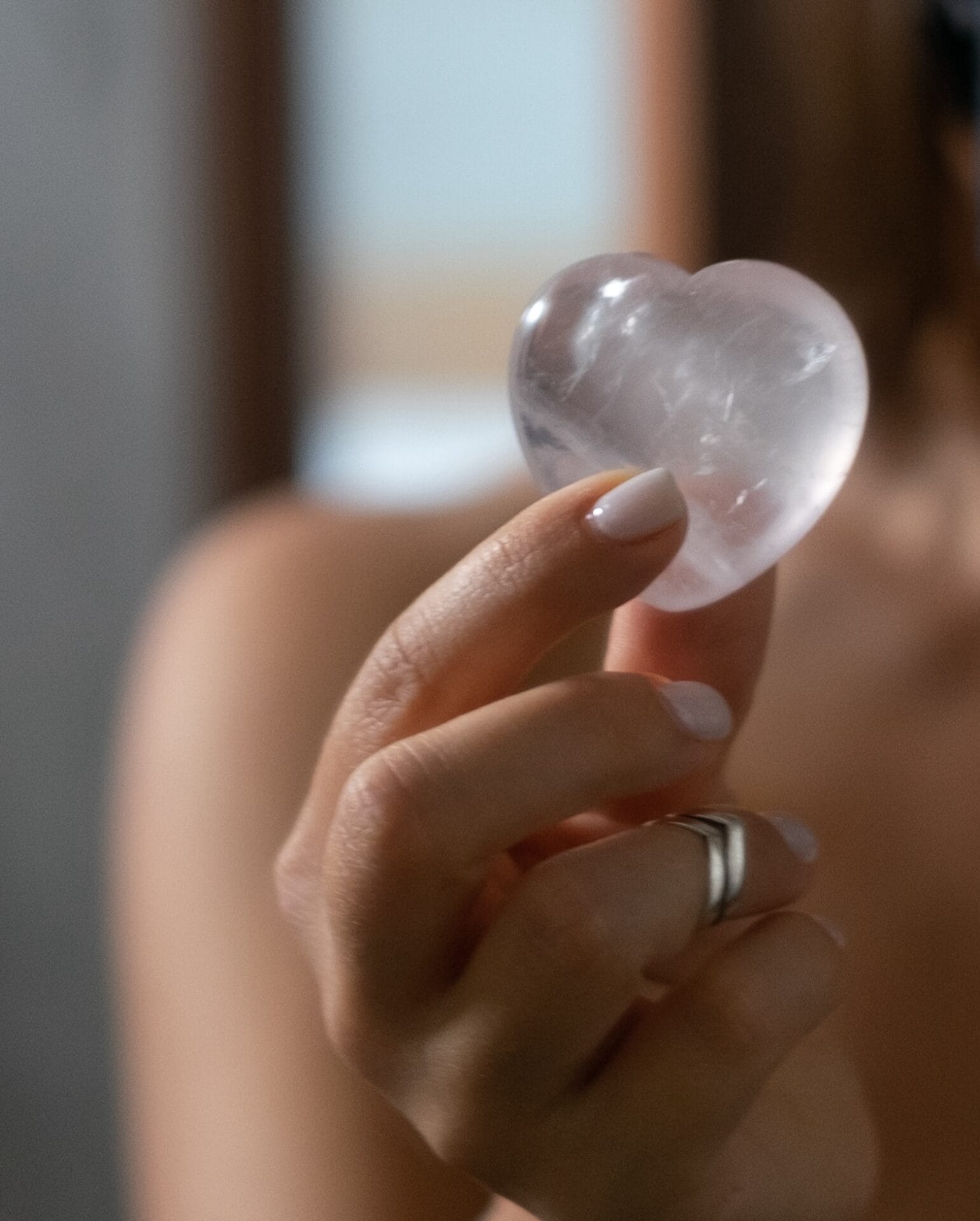 Woman holding in hand rose quartz heart shaped crystal