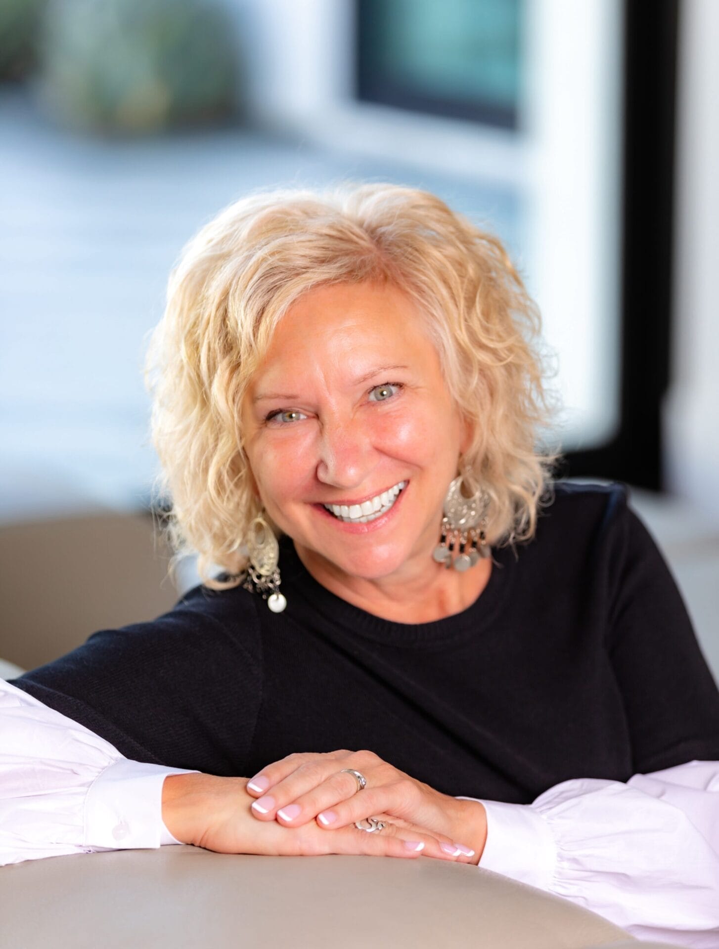 Gayle sitting at a table smiling with hands folded in front of her.
